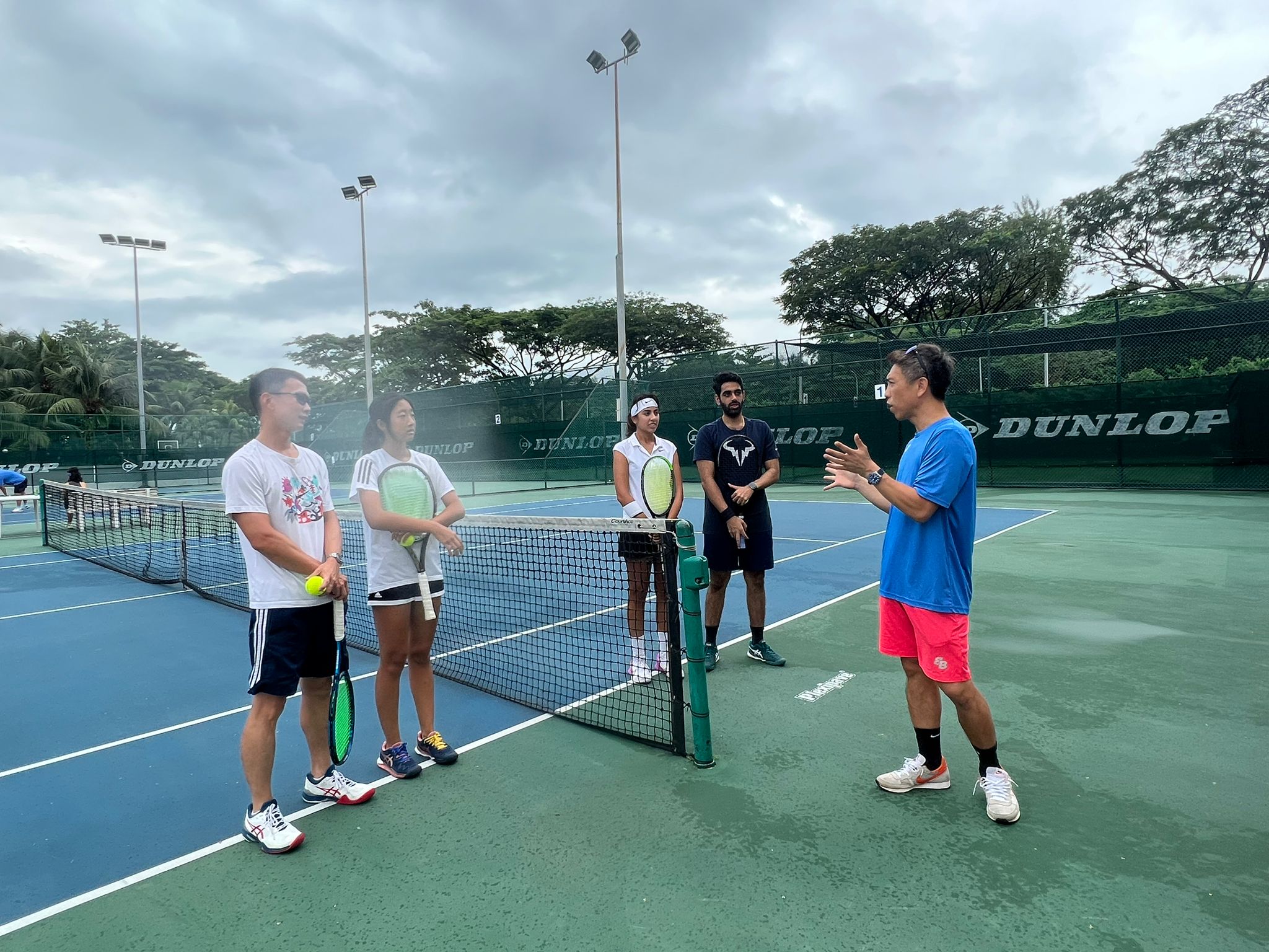 adults attending a group tennis lesson