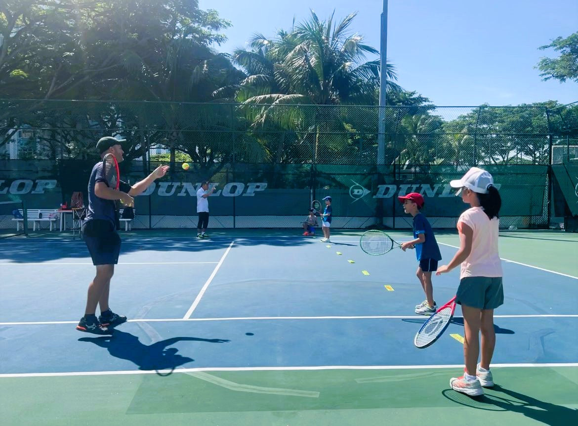 kids tennis lesson on a court with instructor and students